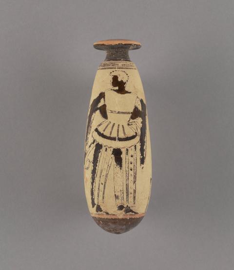 A beige terracotta vessel shaped like a long tear drop. A dark-skinned figure faces left wearing striped pants and a draped mantle holds an ax and an arrow.