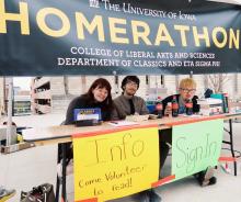 Eta Sigma Phi students, Callie Todhunter, Noah Andrys, and Myles Young, staff the Homerathon booth at the University of Iowa