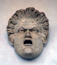 A stone sculpture of a face with an open mouth and furrowed brow