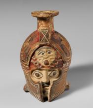 A tan vase with an image of a face with an open mouth