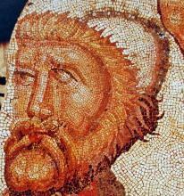 A rust-colored mosaic of a man's face with shaggy hair and a beard