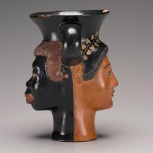 Two handled Greek wine cup with two faces, one of a Black African man and one of a Greek woman