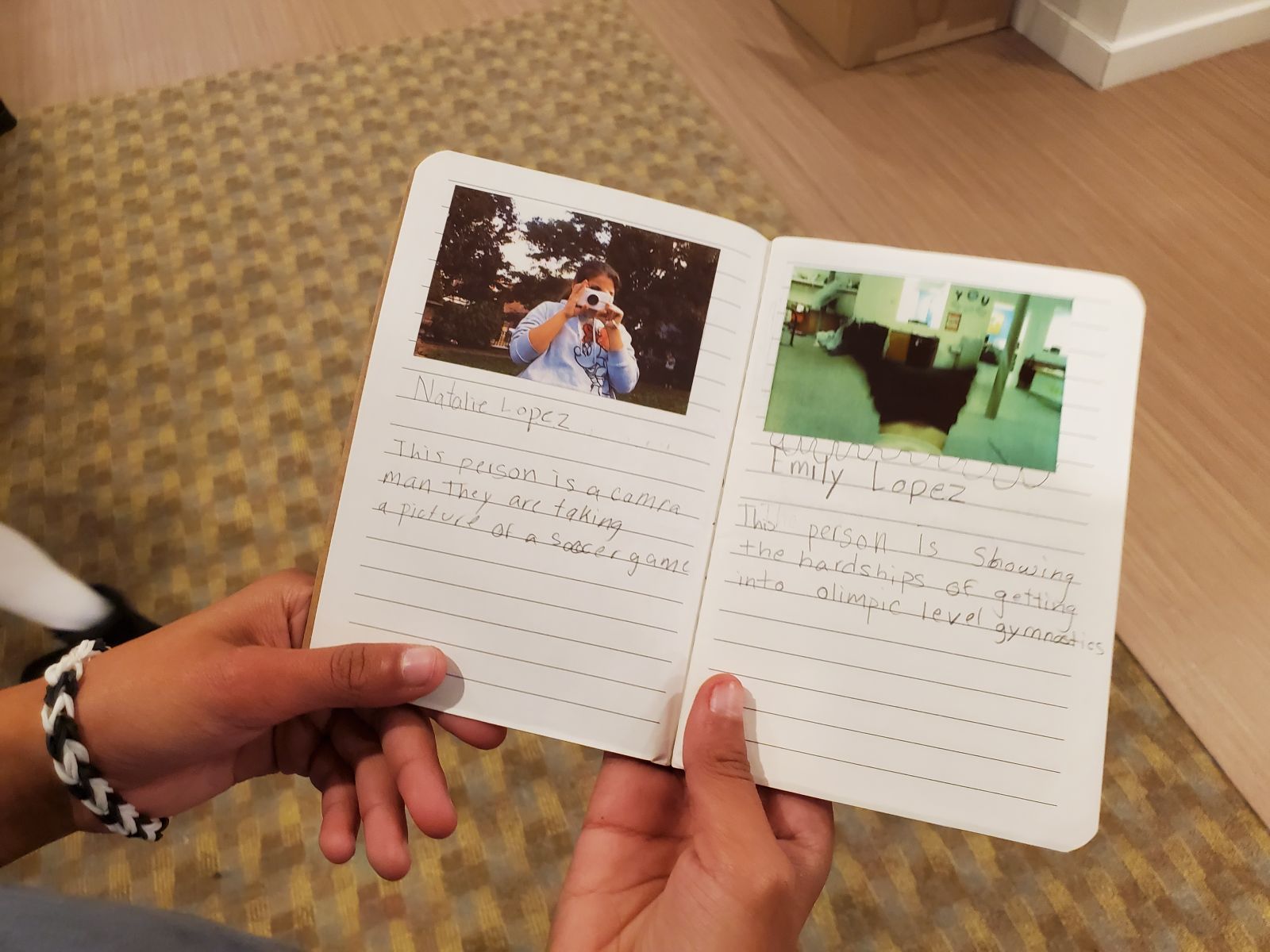 Two hands holding an open journal. On the left side of the page is an image of a girl taking a picture, with writing underneath. On the right is a photo of a room.