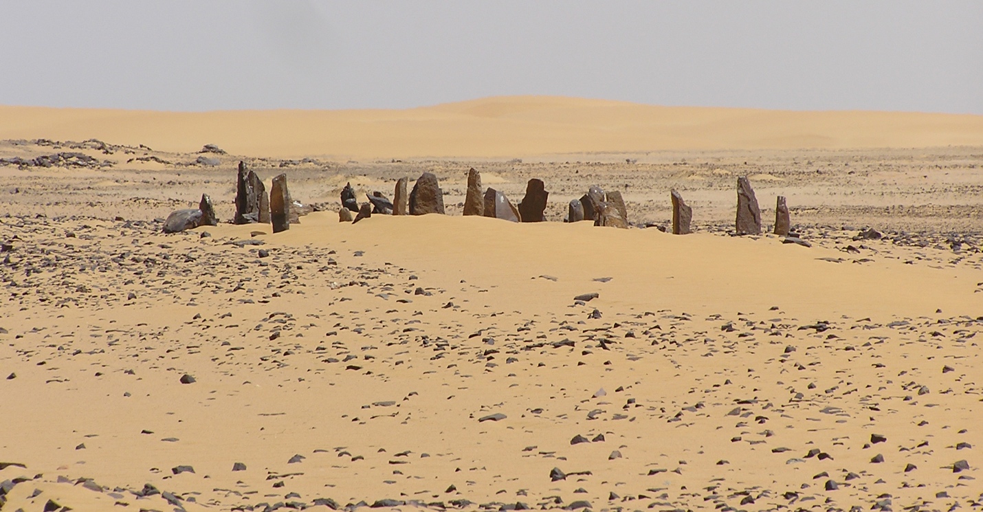 A sandy desert landscape with assorted rocks of different sizes standing upright in the sand.